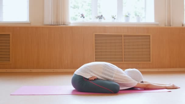 Jonge slanke vrouw liggend op de rug en leunend voorwaarts in lotuspositie — Stockvideo