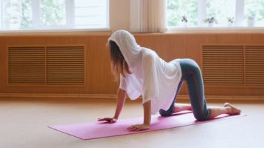 Yoga minderi üzerinde egzersiz beyaz kapüşonlu genç kadın - bel ve omurga için bir egzersiz yapıyor