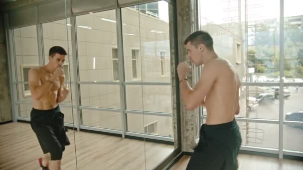 En atletisk man utbildning hans boxning framför spegeln i studion — Stockvideo