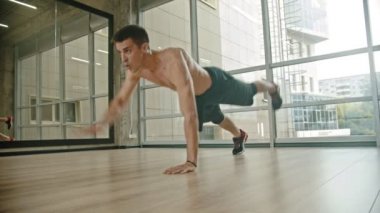 Stüdyoda çıplak gövde eğitimi ile atletik bir adam - itme up yapıyor ve bir yandan ayakta ve ileri başka bir el çekerek
