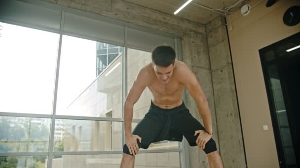 Боксер-спортсмен отдыхает после тренировки - опирается на колени и тяжело дышит — стоковое видео
