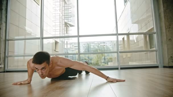 Un uomo atletico con busto nudo che si allena in studio appoggiandosi alle mani e mantenendo l'equilibrio sopra il suolo — Video Stock