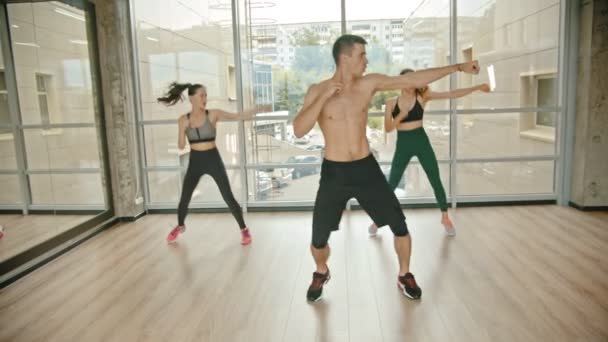 Entrenamiento de fitness en el estudio - dos mujeres jóvenes entrenando con su entrenador - saltando en el acto y golpeando — Vídeo de stock