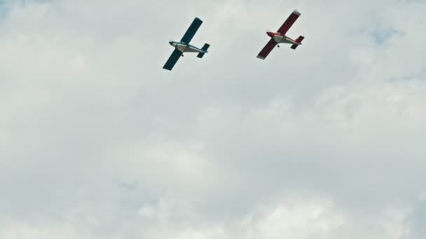 Bulutlu gökyüzünde uçan iki askeri uçak - mavi ve kırmızı uçaklar — Stok video