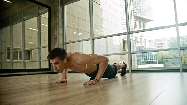 An athletic shirtless man training in the studio - doing push ups — Stock Photo, Image