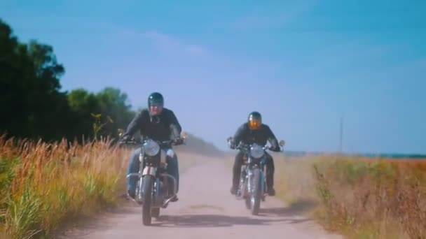 Két férfi motorkerékpárosok lovaglás motorbiciklit a rozs területén — Stock videók