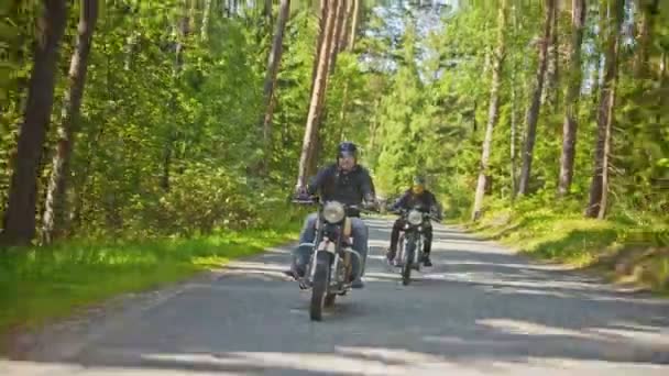 Two brutal men motorcyclists riding a motorbike in the forest - a camera following the moves of bikers — Stock Video