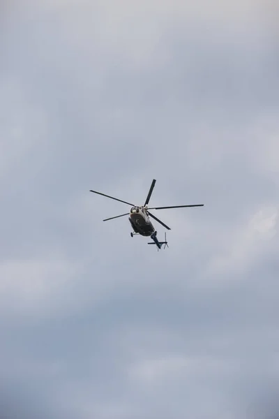 Ein Hubschrauber fliegt in den grauen wolkenverhangenen Himmel — Stockfoto