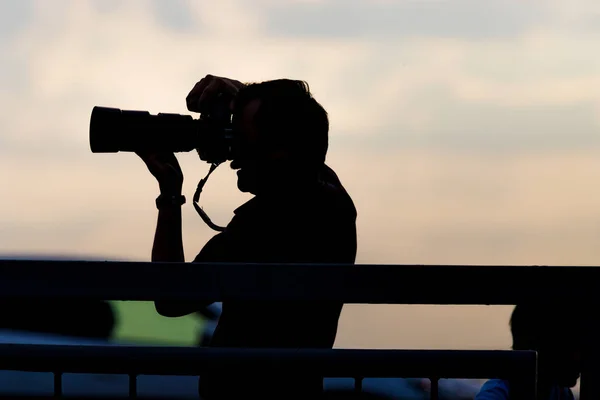 Fotografo silhouette con la sua macchina fotografica su uno sfondo di primo tramonto — Foto Stock