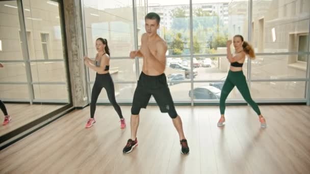 Entrenamiento de fitness en el estudio - dos mujeres jóvenes entrenando con su entrenador - saltando en el acto - realizando ejercicios repetitivos de resistencia — Vídeos de Stock