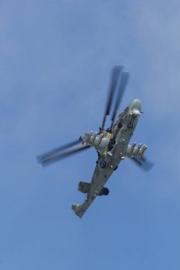 Mavi gökyüzünde uçan bir askeri kamuflaj helikopteri