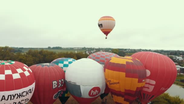 18-07-2019 Suzdal, Rusko: různé pestrobarevné vzduchové balónky se sunují přes pole-různé nápisy značek na balonách — Stock video