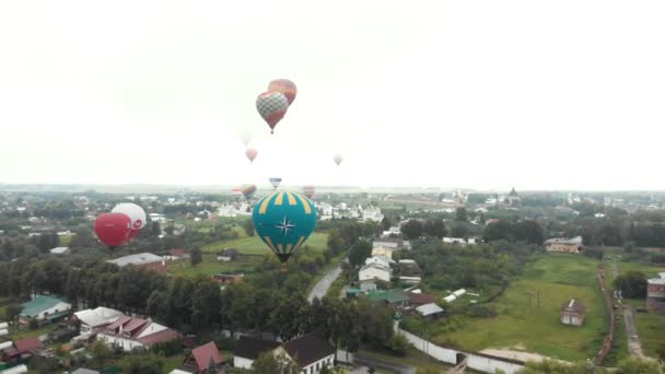 18-07-2019 Suzdal, Rusko: různé obrovské vzduchové balónky létají přes malé městečko-různé nápisy značek na balonách — Stock video