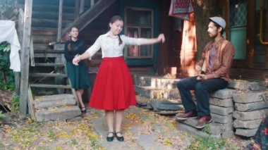 Müzik tarafından dans kırmızı etekli bir kadın - balalaika oynayan bir adam - ellerini çırpan başka bir kadın