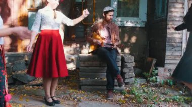 Renkli giysiler içinde müzik dans ve eğlenmek kadınlar - balalaika oynayan bir adam - güneş ışığı ağaçların arasından alıyorum