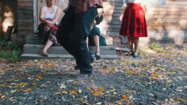 Balalaika çalan bir kadın ve kır evinin yakınında folklor dansı olan bir adam.