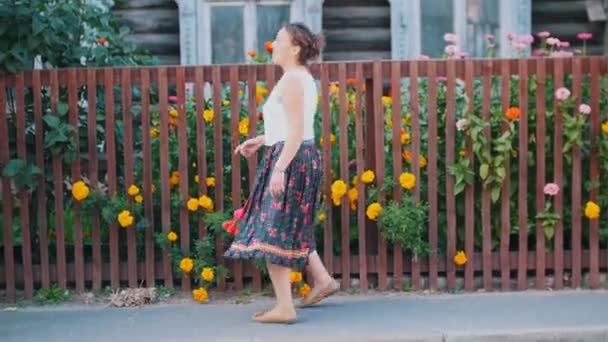フェンスの向かいの通りで踊る長いスカートの女性 — ストック動画