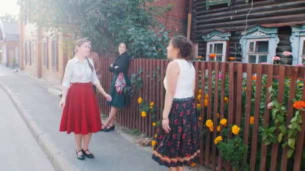 Young women in long skirts dancing folk dances by the fence on the street — Stock Video