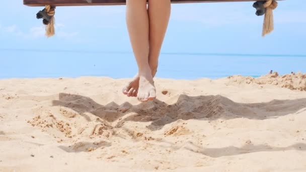 Beine einer jungen Frau schwingen auf einer Schaukel am Strand — Stockvideo