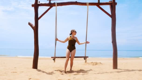 Una giovane donna distratta che oscilla su un'altalena sulla spiaggia — Video Stock