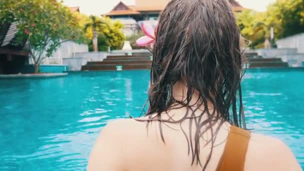 Una joven con el pelo mojado y la piel limpia caminando en la piscina — Vídeo de stock