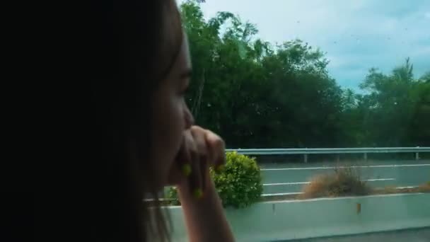 Μια νεαρή γυναίκα κάθεται στο λεωφορείο και κοιτάζει στο παράθυρο-κοιτάζοντας το δρόμο και τα αυτοκίνητα — Αρχείο Βίντεο