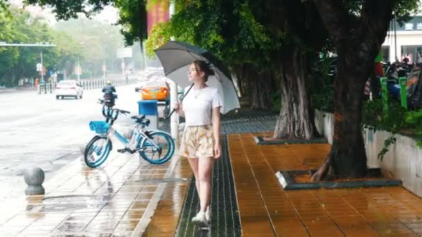 Una joven caminando por la calle China bajo la lluvia sosteniendo un paraguas — Vídeos de Stock