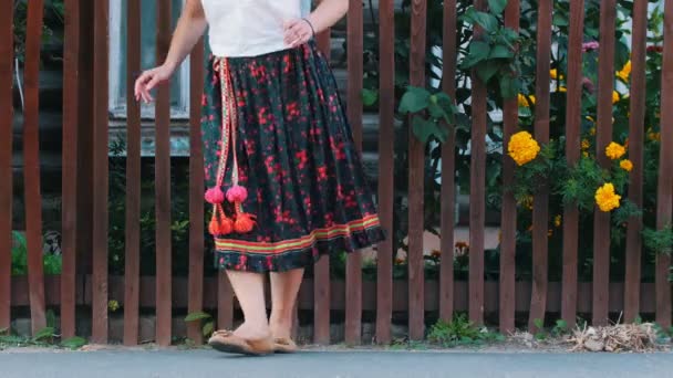 長いカラフルなスカートを着た女性が路上のフェンスの前で踊る — ストック動画