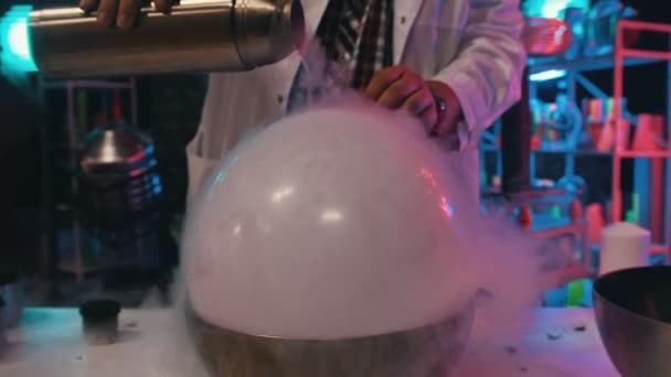 Scientist pours the liquid nitrogen on the balloon - show of chemical reactions — Stock Video