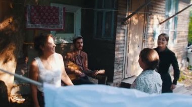 Kadınlar dans ve kır evi yakınında eğlenmek - balalaika oynayan bir adam