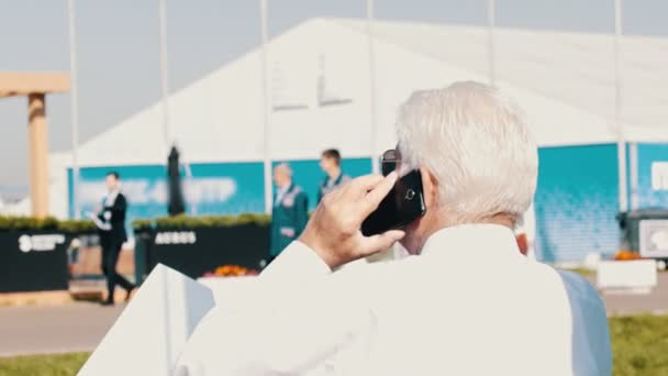 Retrato del viejo empresario hablando por teléfono al aire libre — Vídeos de Stock