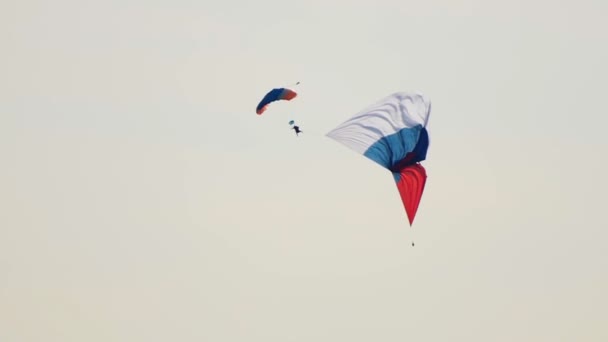 Egy ember repül az égen nyitott ejtőernyős és zászló — Stock videók