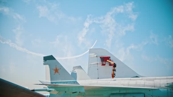 Aviones reactivos volando en el cielo y realizando piruetas dejando líneas de humo - personas pintando una parte de un avión en primer plano — Vídeos de Stock