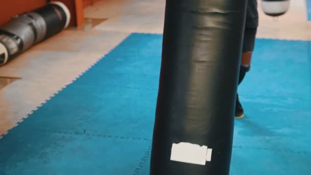 Человек культурист поднимает и несет боксерскую грушу на плече — стоковое видео