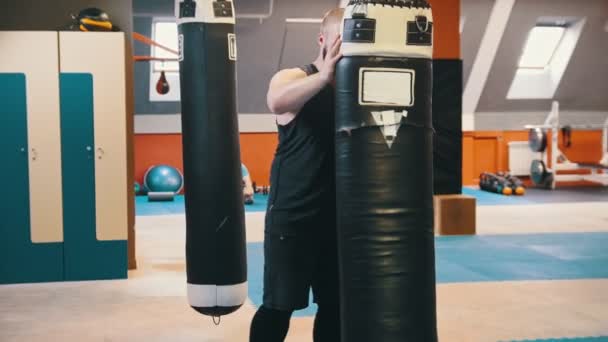 Muž, který kulturista zvedne nahoru a nosí boxovací pytel na rameni v tělocvičně — Stock video