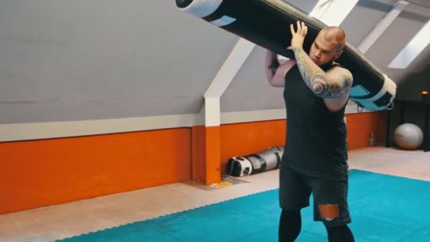 Ein Mann Bodybuilder hockt mit schwerem Boxsack auf der Schulter — Stockvideo