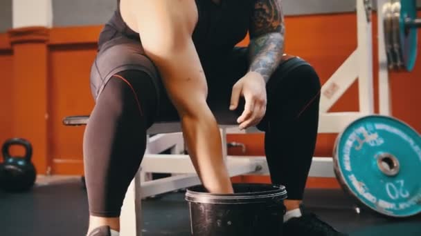 Un homme musclé couvrant ses mains de talc et l'applaudissant assis dans la salle de gym — Video