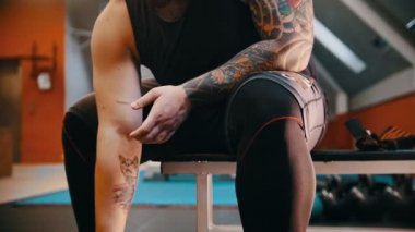 Spor salonunda talkın içinde ellerini kaplayan kaslı dövmeli bir adam