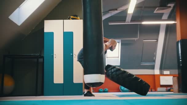Een dikke getatoeëerde man bodybuilder draait over de band op de vloer en het verplaatsen met deze beweging-powerlifting oefeningen — Stockvideo
