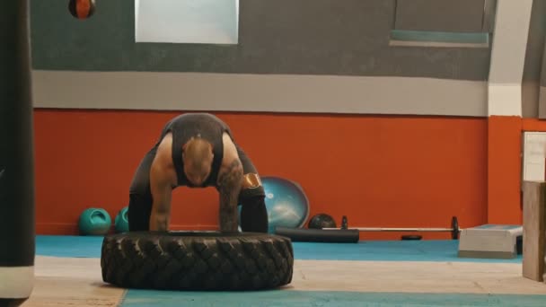 一个男人的健美运动员把轮胎放起来，把它掉回地板上 — 图库视频影像
