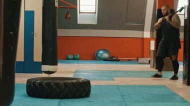 Çekiçle bir lastiğe çarpan bir adam vücut geliştirmeci