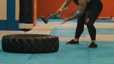 Çekiçle büyük bir lastiğe vuran bir adam vücut geliştirmeci.