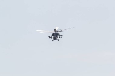 Beyaz gökyüzünde uçan dev bıçakları olan bir askeri helikopter