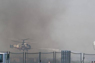 Bir yangın helikopteri dumanlı zeminüzerinde bir su akışı yayılır
