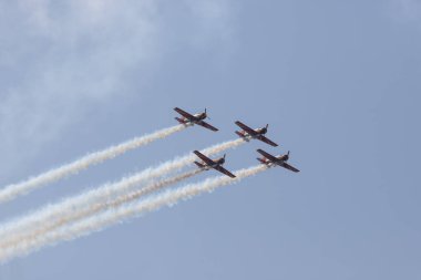 Mavi gökyüzünde uçan ve duman izleri bırakan bir gösteri gerçekleştiren dört askeri jet