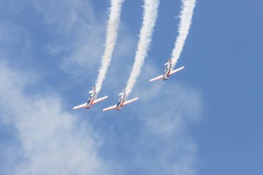 Üç askeri jet gökyüzünde uçuyor ve duman izleri bırakarak bir gösteri sergiliyor