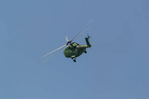 A zöld katonai helikopter vékony pengével repül el az égen — Stock Fotó