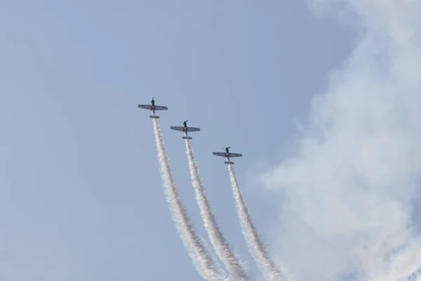 Três jatos coloridos voando no céu azul e realizando um show deixando marcas de fumaça — Fotografia de Stock