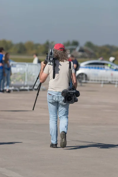 Un uomo fotografo che cammina sulla zona e tiene in mano la sua attrezzatura — Foto Stock