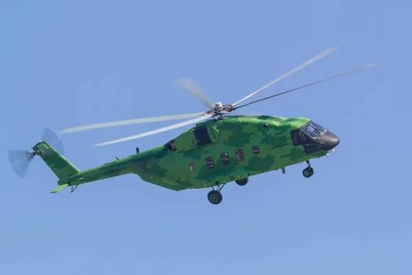 Um helicóptero militar verde brilhante voando no céu azul vista lateral — Fotografia de Stock